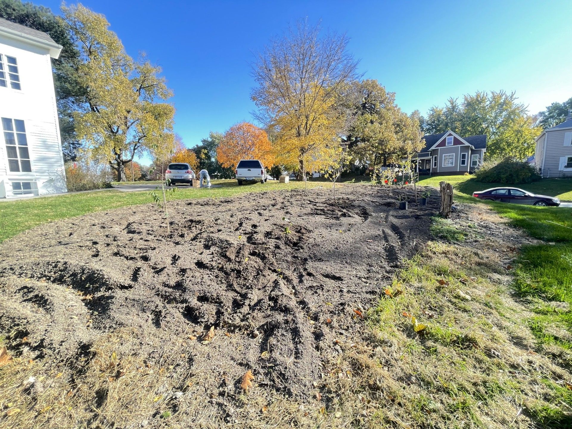 Freshly graded dirt mound beside a grassy suburban street under a clear blue sky