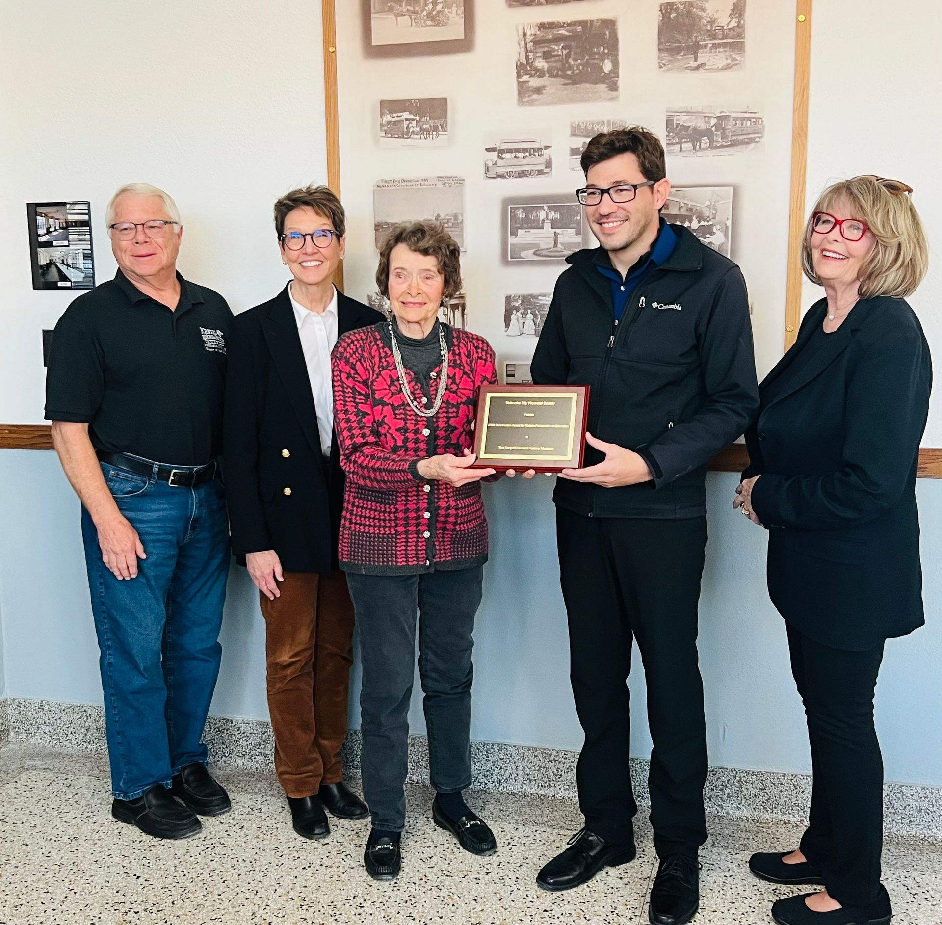 A group of people standing in front of a wall holding a plaque