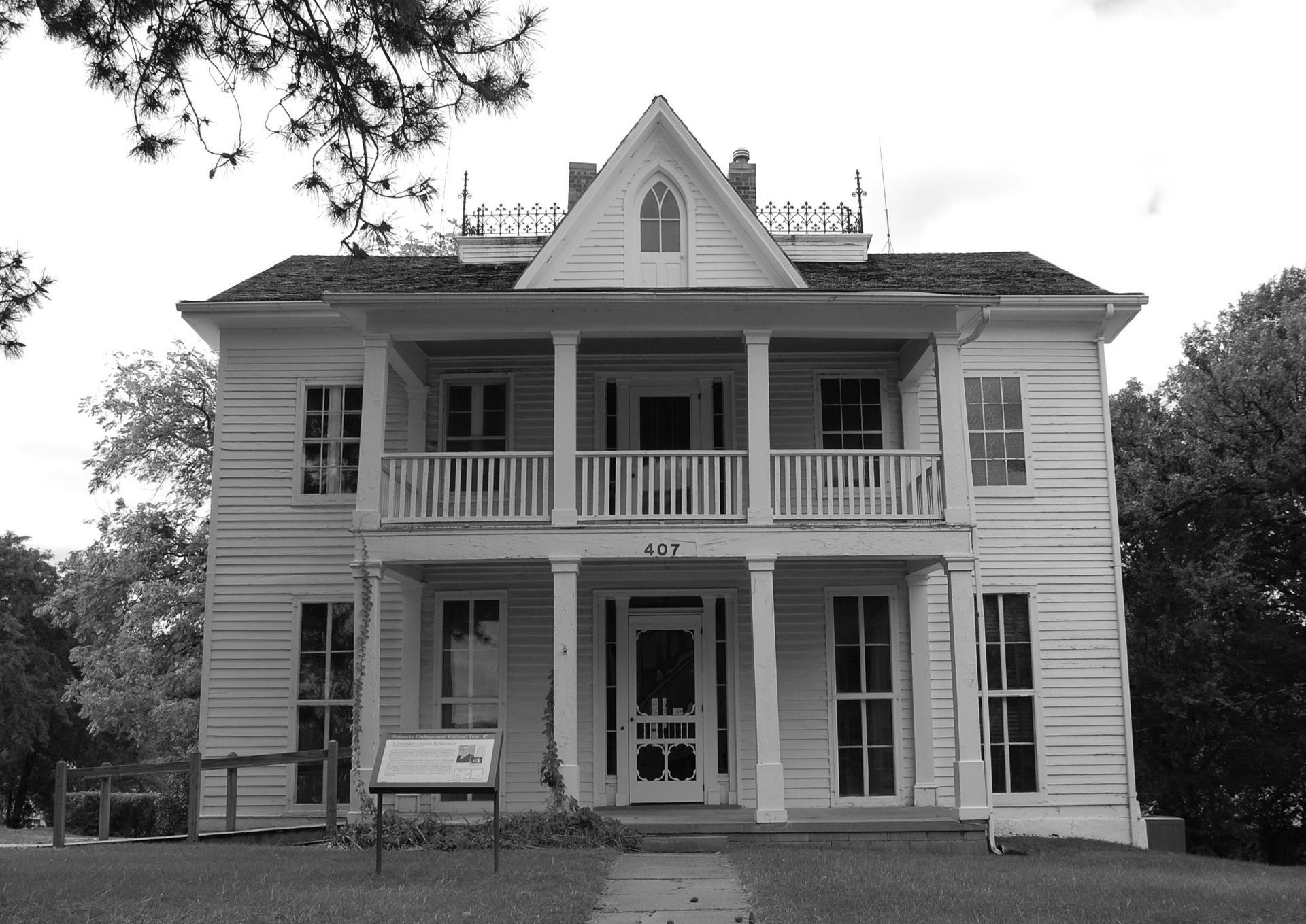 Black-and-white photo of a two-story Victorian house with a porch and gabled roof.