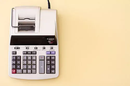 A white, print-out calculator with a black display and keyboard, on a yellow background.