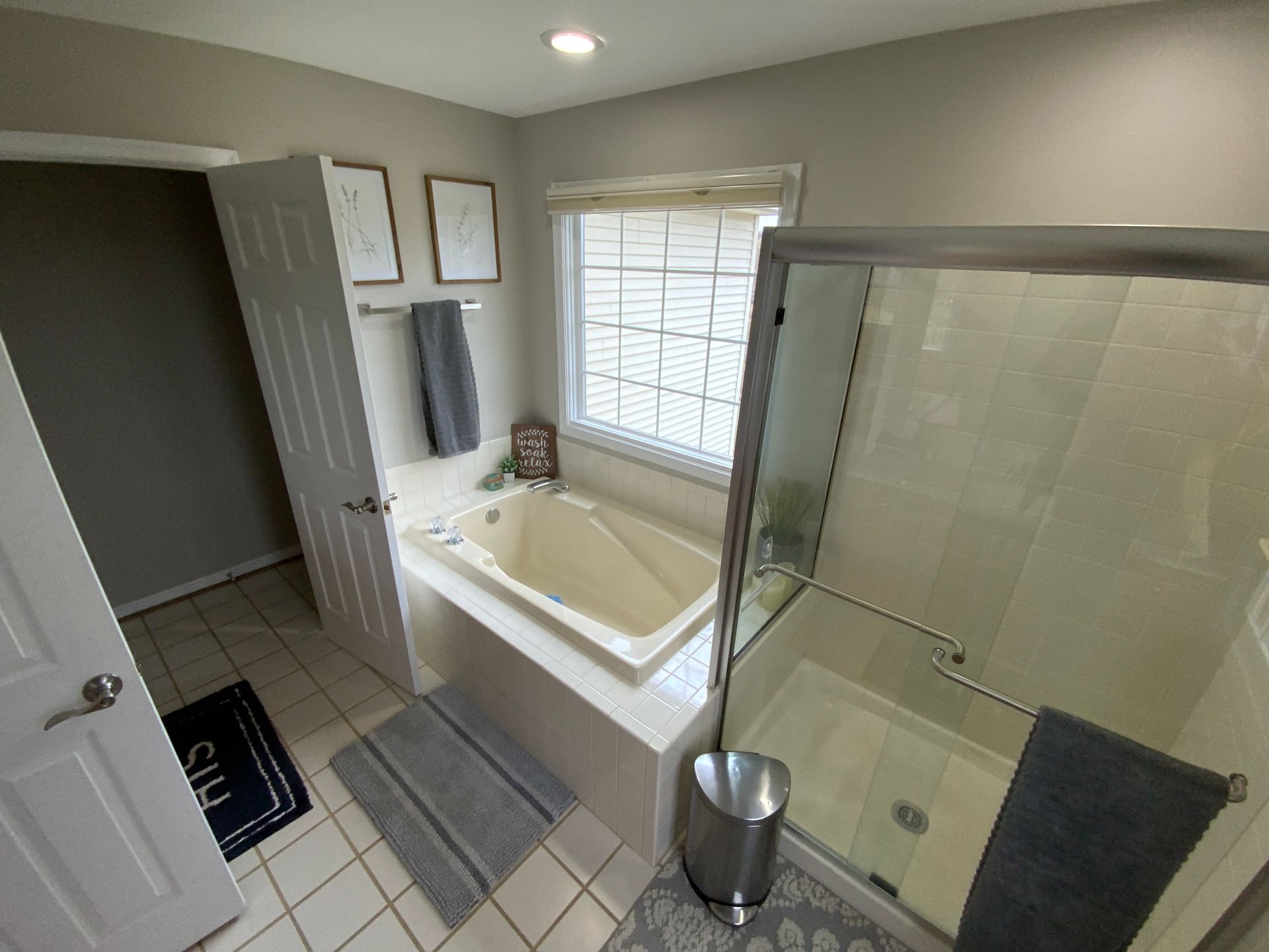 A bathroom with a tub , shower , and window.