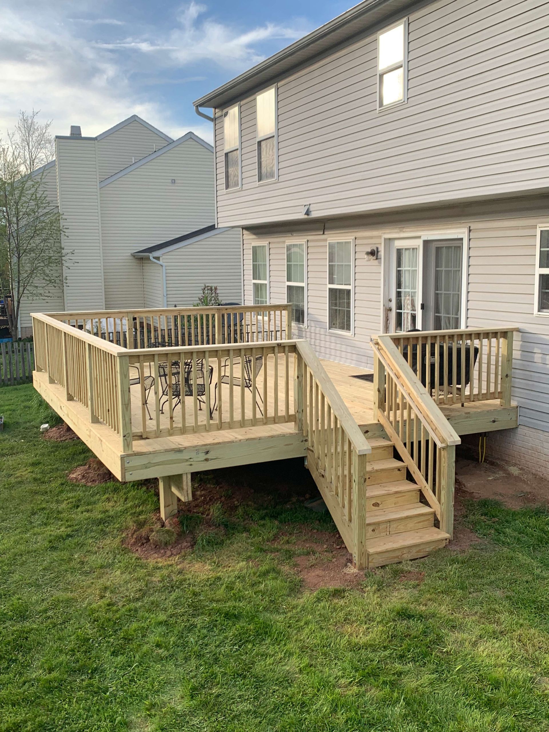 A large wooden deck with stairs is in the backyard of a house.