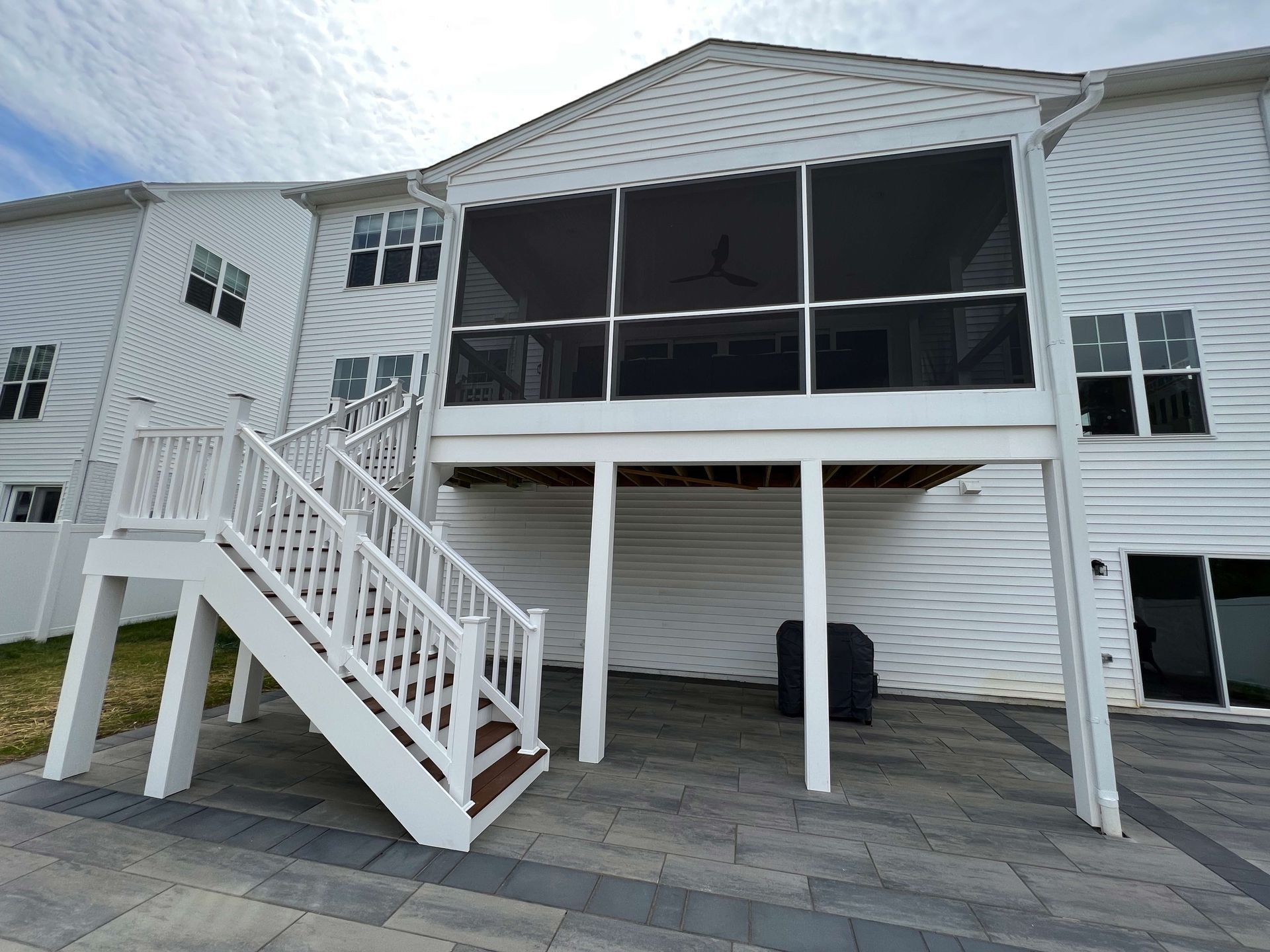 A white house with a screened in porch and stairs