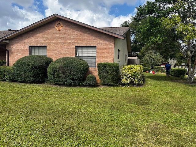 A brick house with a lush green lawn in front of it.