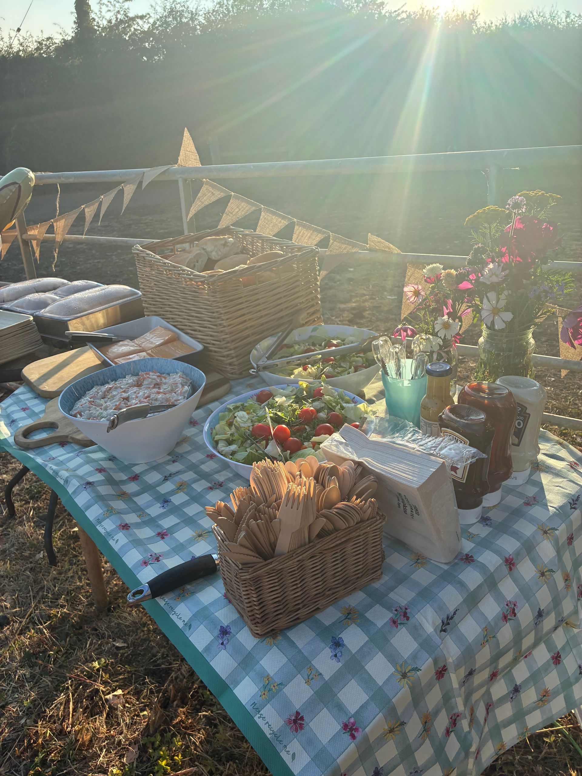 A group buffet table with gingham cloth, bunting, salads and bread at The Apple Farm — barbecue catering for group getaways in Warwickshire