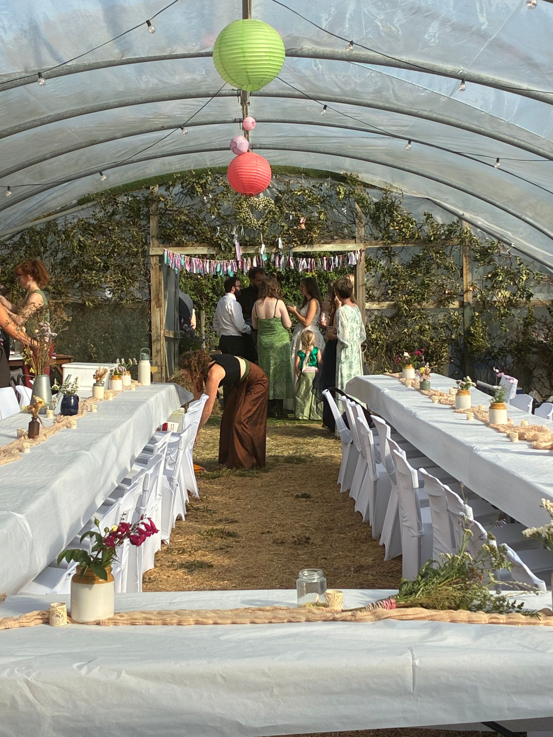 The Apple Farm's polytunnel dressed for a long-table group celebration with lanterns and bunting — undercover group dining near Stratford-upon-Avon