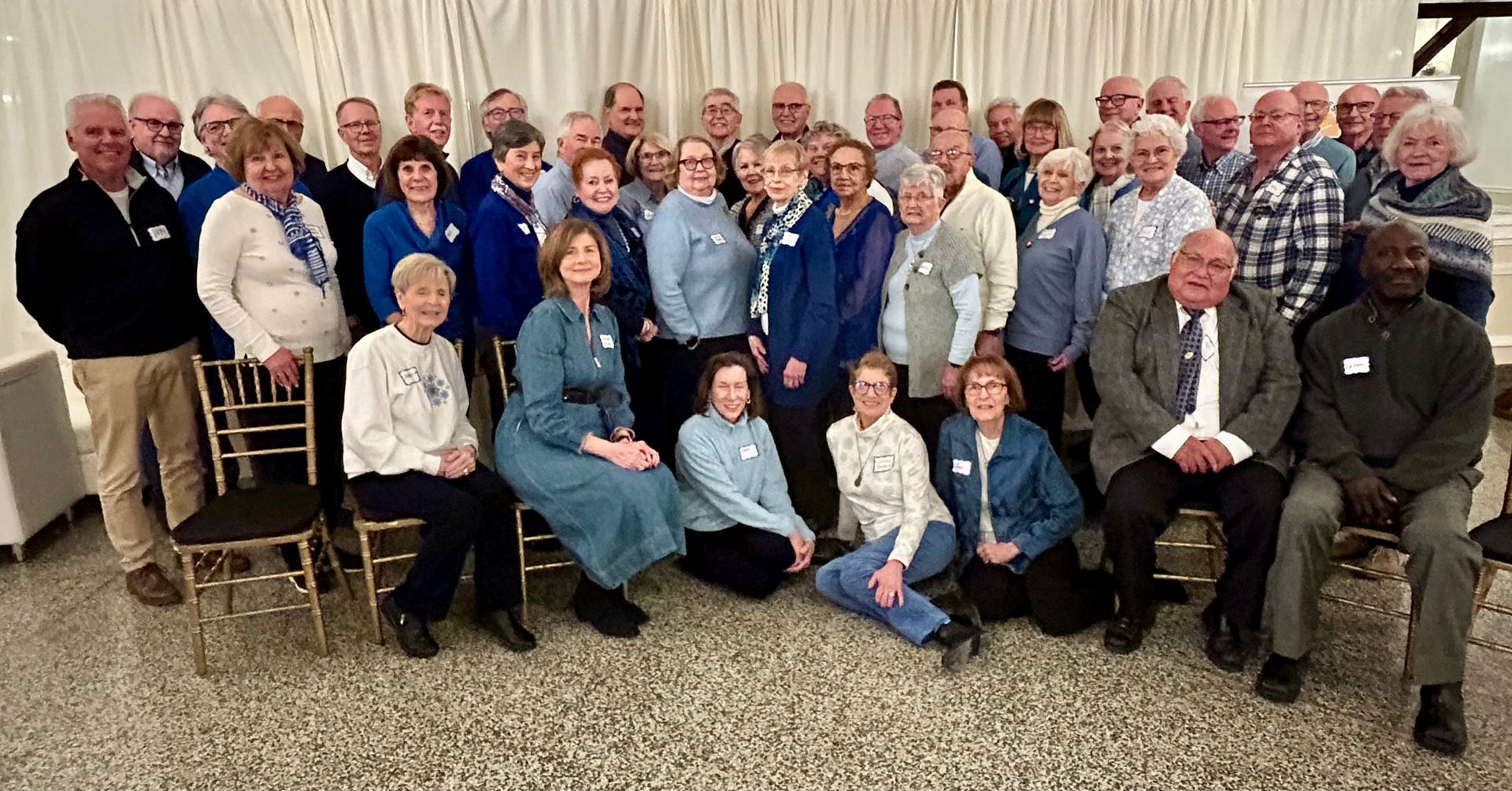 Group of people in blue and white attire, indoors, posing for a photo.