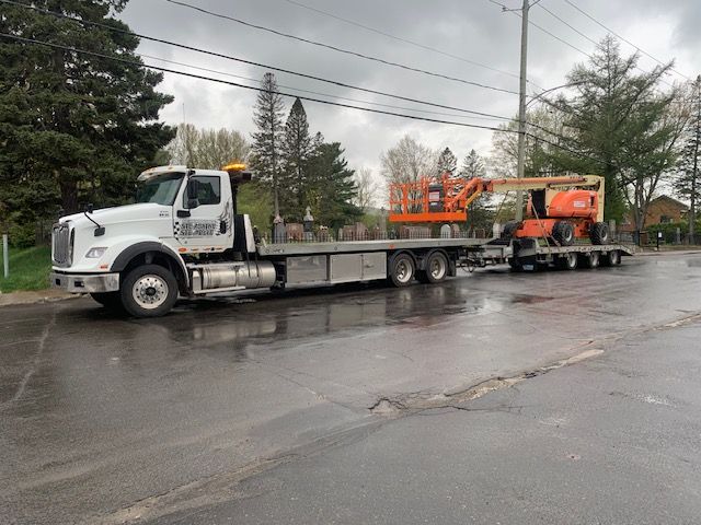 Une dépanneuse transporte une grue à l'arrière.