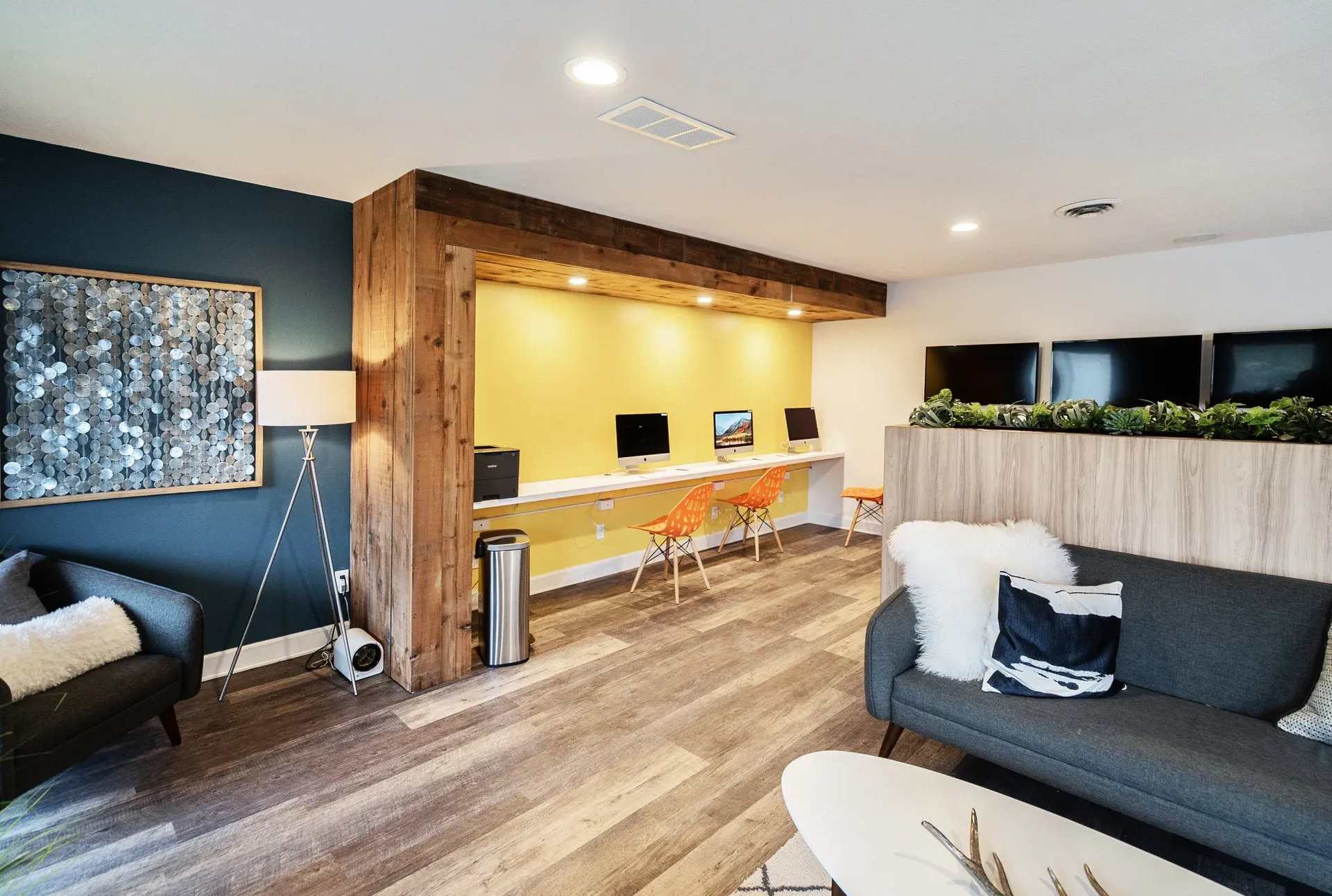 Community lounge with a yellow workstation wall, computers, and seating.
