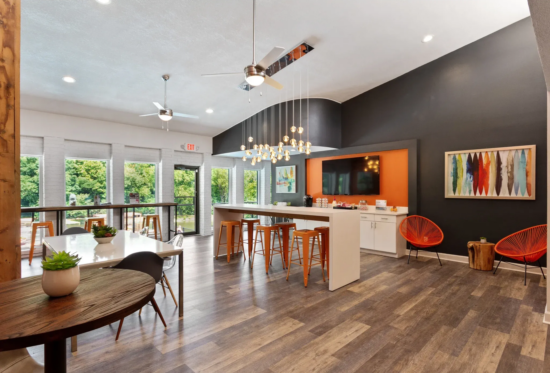 Modern community lounge with a white kitchen island, bar seating, and large windows.