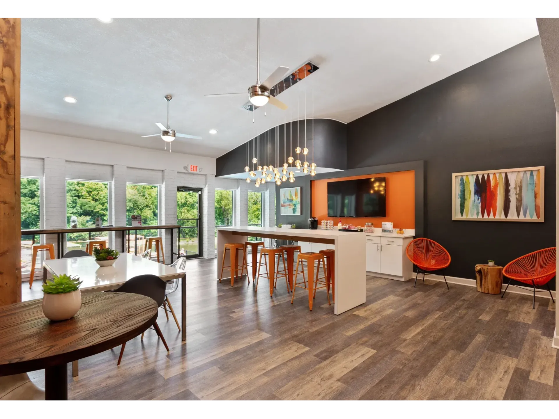Modern community lounge with a white kitchen island, bar seating, and large windows.