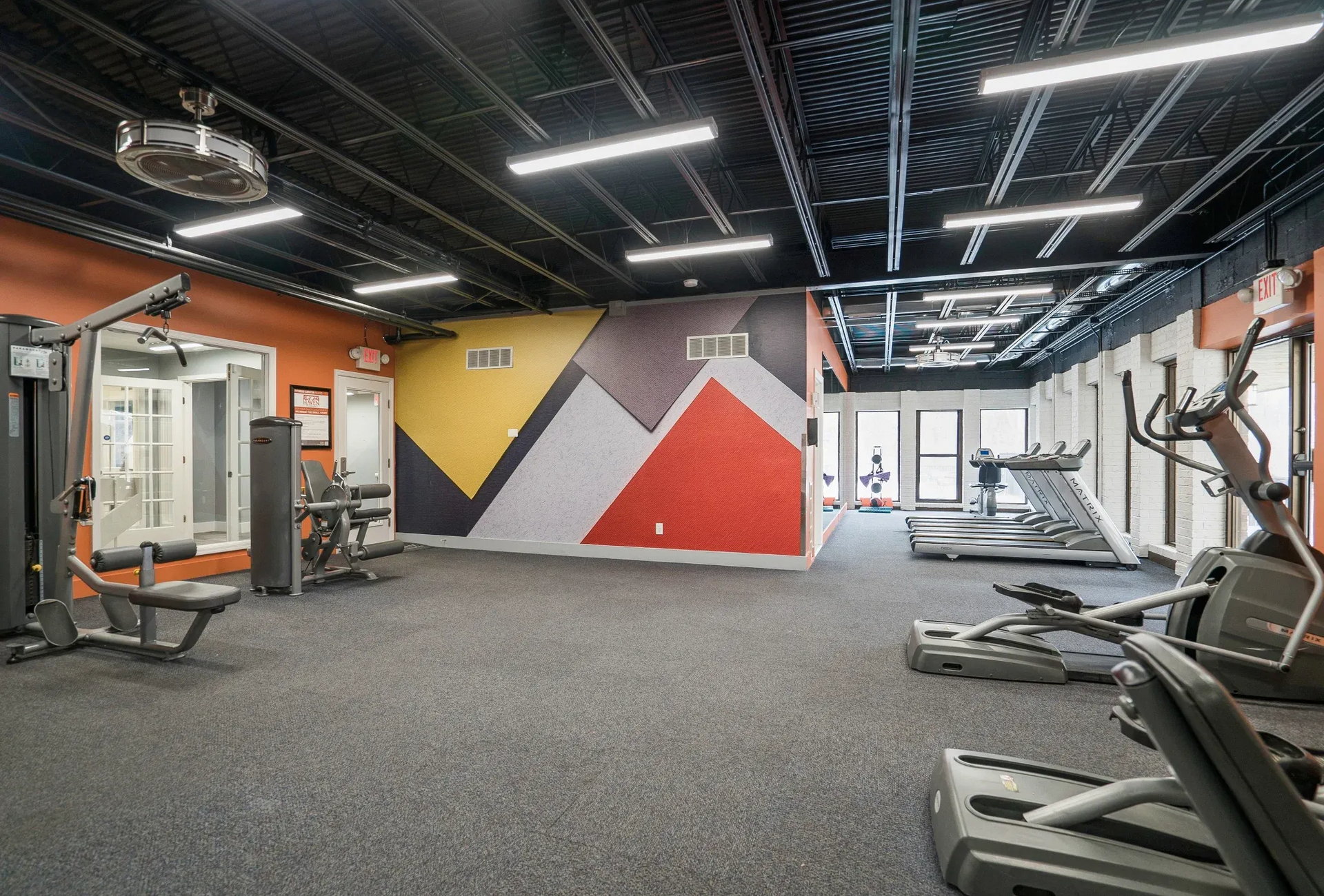 Bright fitness center with treadmills, weight machines, and colorful wall art.