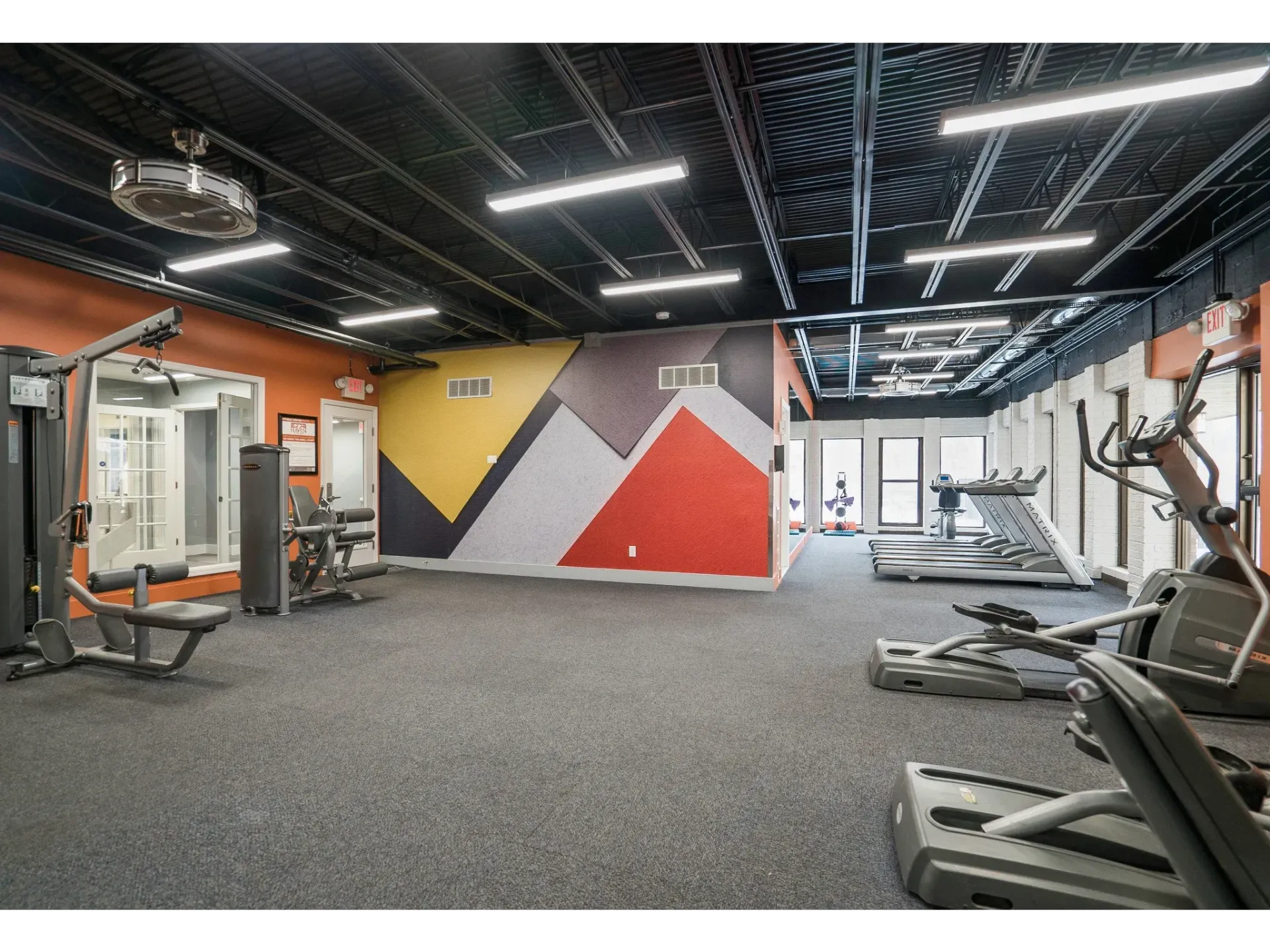 Bright fitness center with treadmills, weight machines, and colorful wall art.