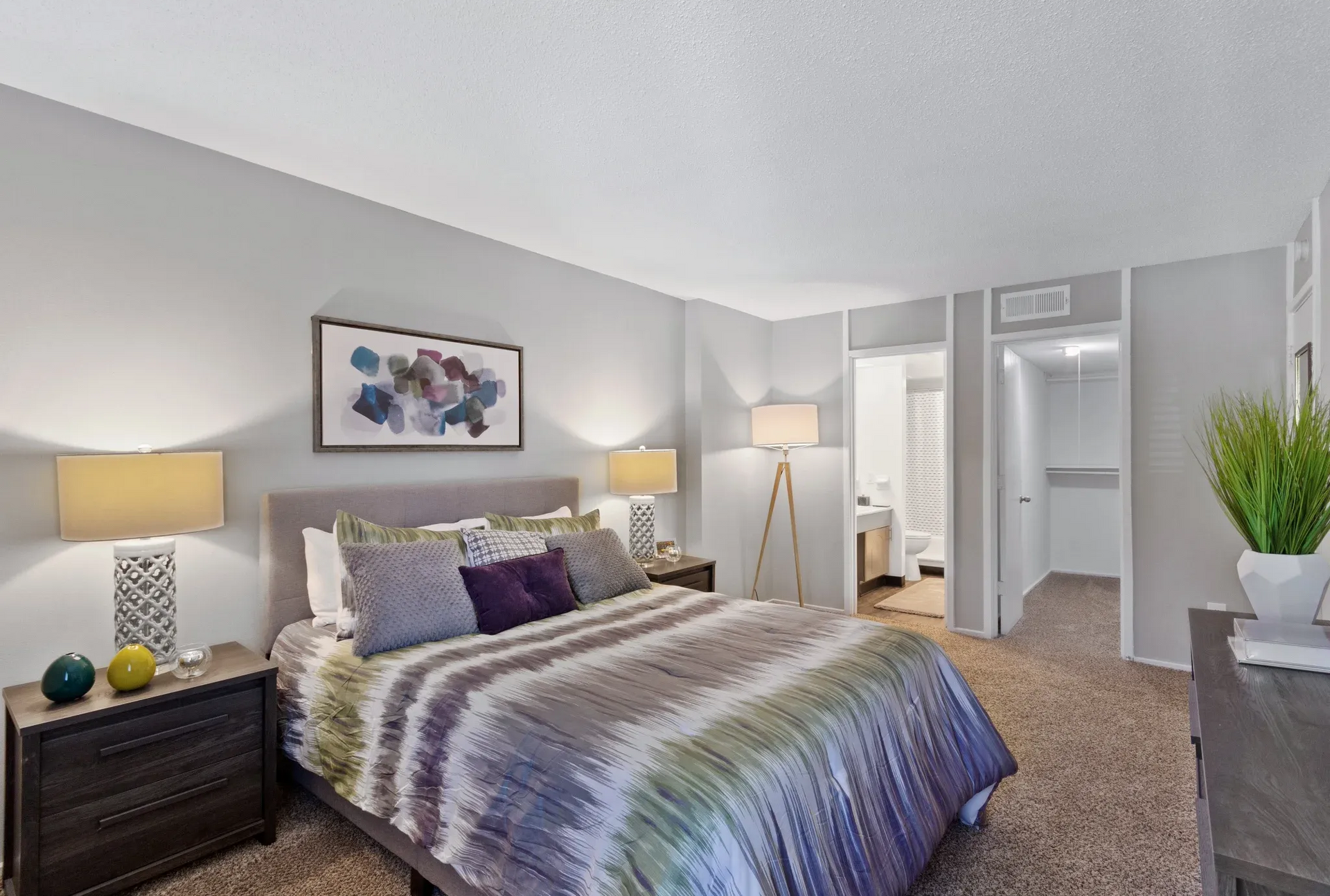 Bedroom with a king bed, two nightstands, lamps, and a doorway to the bathroom.