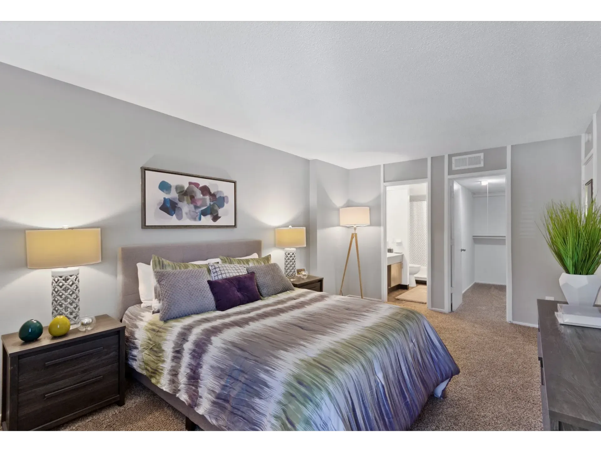 Bedroom with a king bed, two nightstands, lamps, and a doorway to the bathroom.
