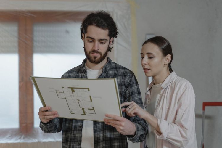 Two people reviewing a floor plan together in a bright room