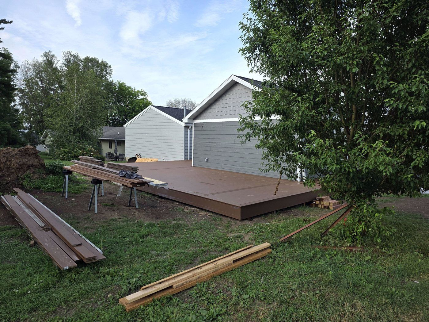 Wooden deck under construction in a backyard beside a house and trees