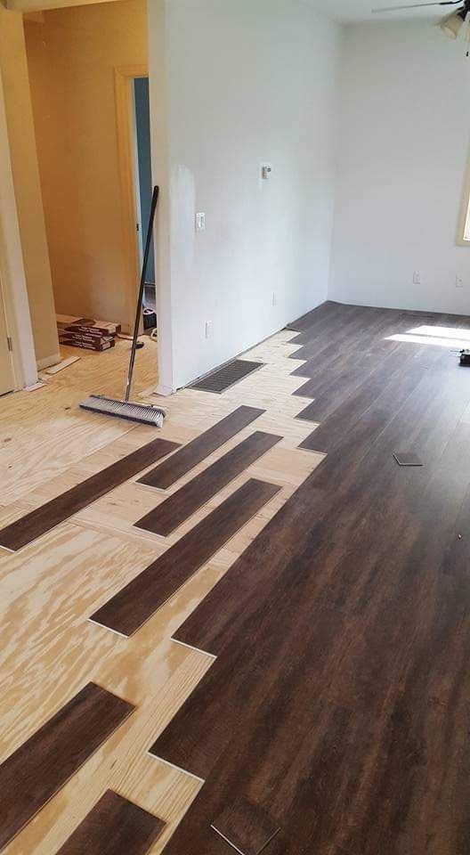 Partially installed wood flooring in a room, with planks laid over exposed subfloor near a doorway.
