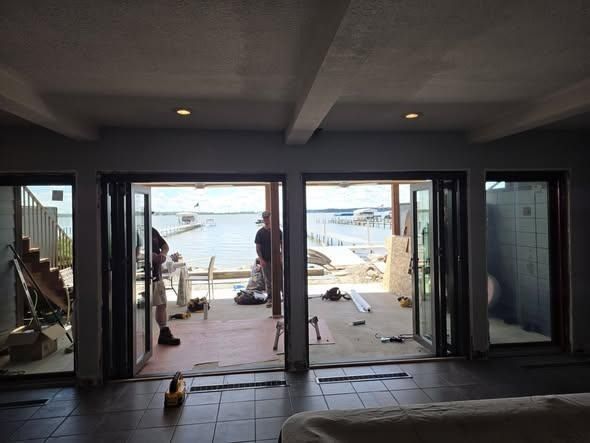 Empty room with sliding glass doors opening to a waterfront view during renovation