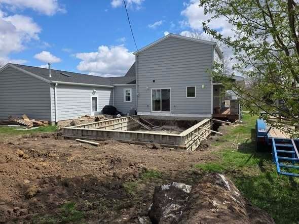 House with unfinished backyard patio and dirt work under a cloudy sky
