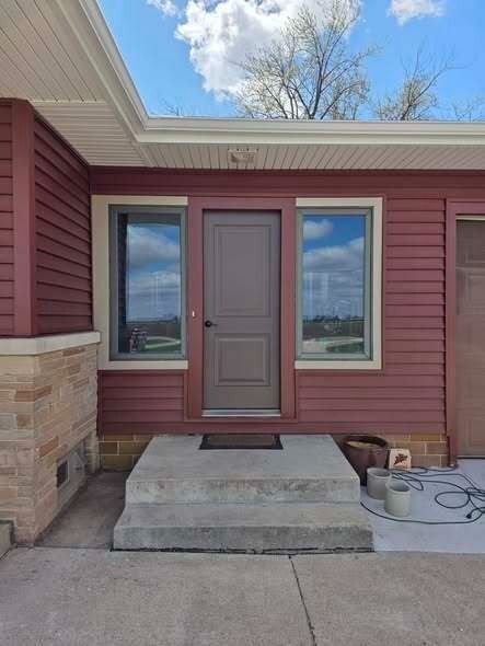 Front entrance with pink siding, tan door, and concrete steps under a covered porch.