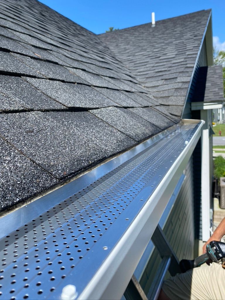 White house gutter system. Angled view of gutter, downspout, and roof trim against siding.