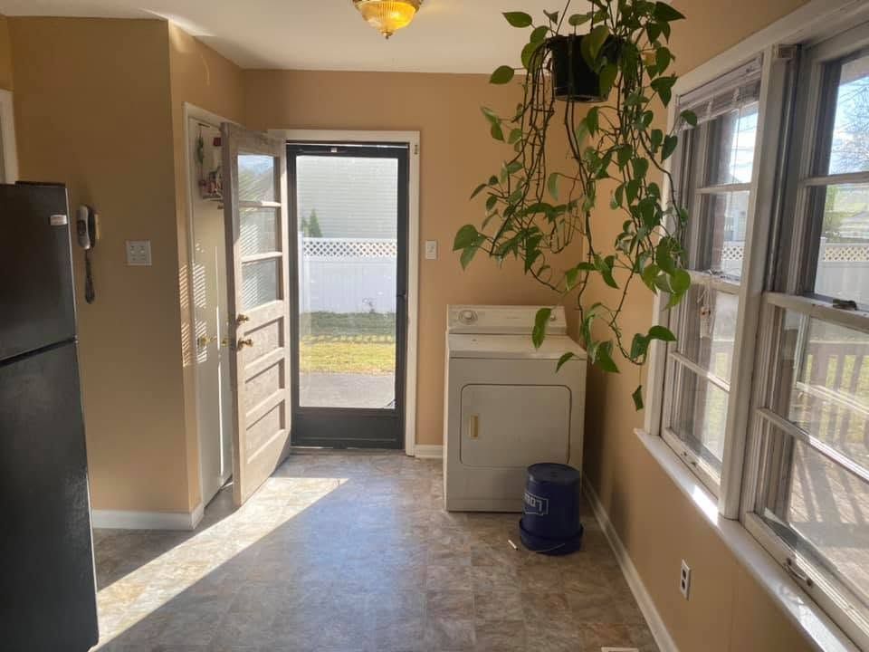 Bright kitchen with open door, sunlight, washer and dryer, and large windows.