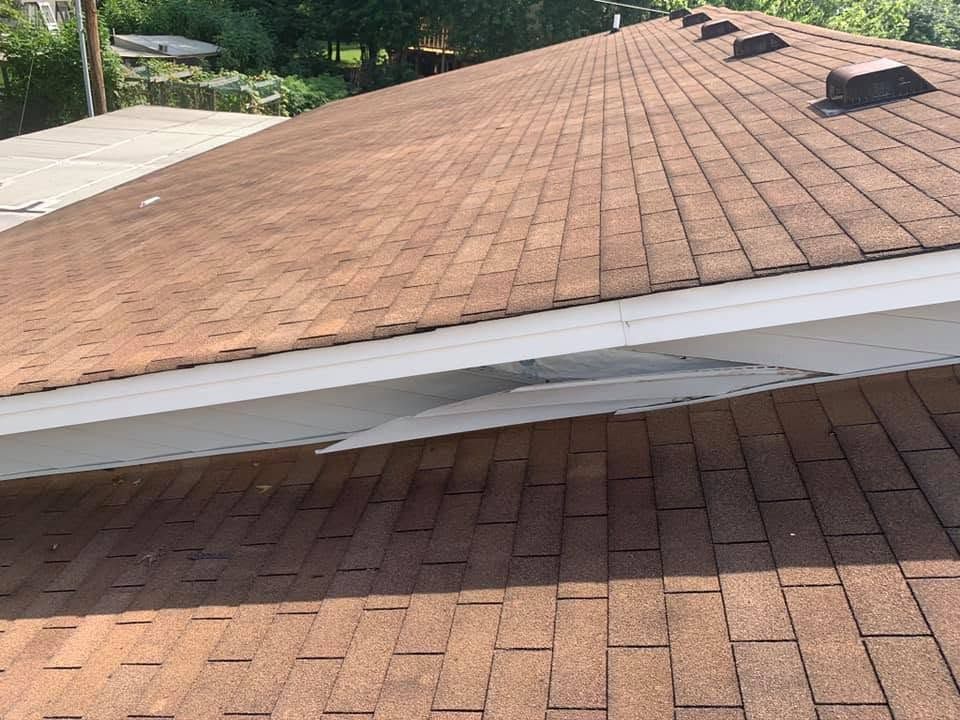 Damaged roof with a sagging white fascia between two brown shingle sections