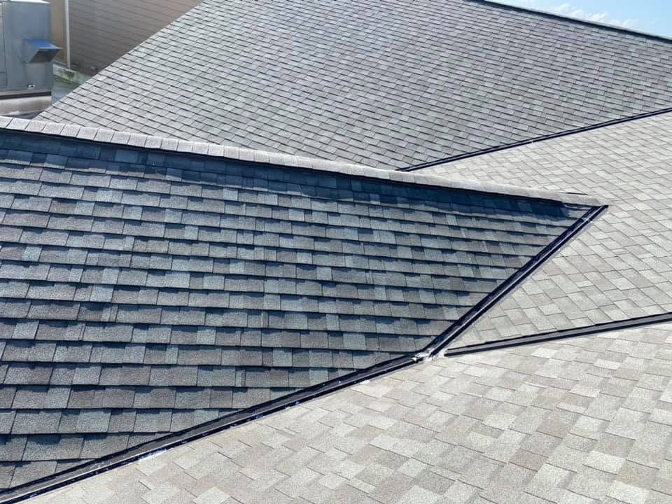 Several shingled roof sections meeting at angled seams under daylight