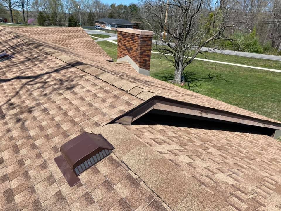 Shingled roof with a dormer vent and chimney on a sunny day overlooking a green yard