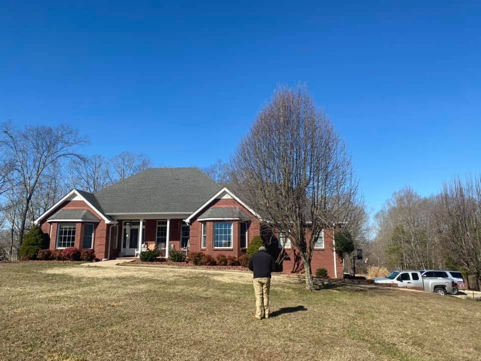 Brick house with a person standing on the lawn under a clear blue sky