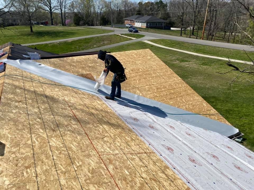 Worker installing roofing underlayment on a sloped roof