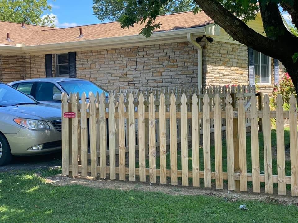 Suburban house with a wooden picket fence and a silver car parked in the driveway