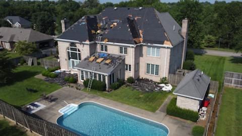 Aerial view of a large beige house with a backyard pool, patio, and fenced lawn