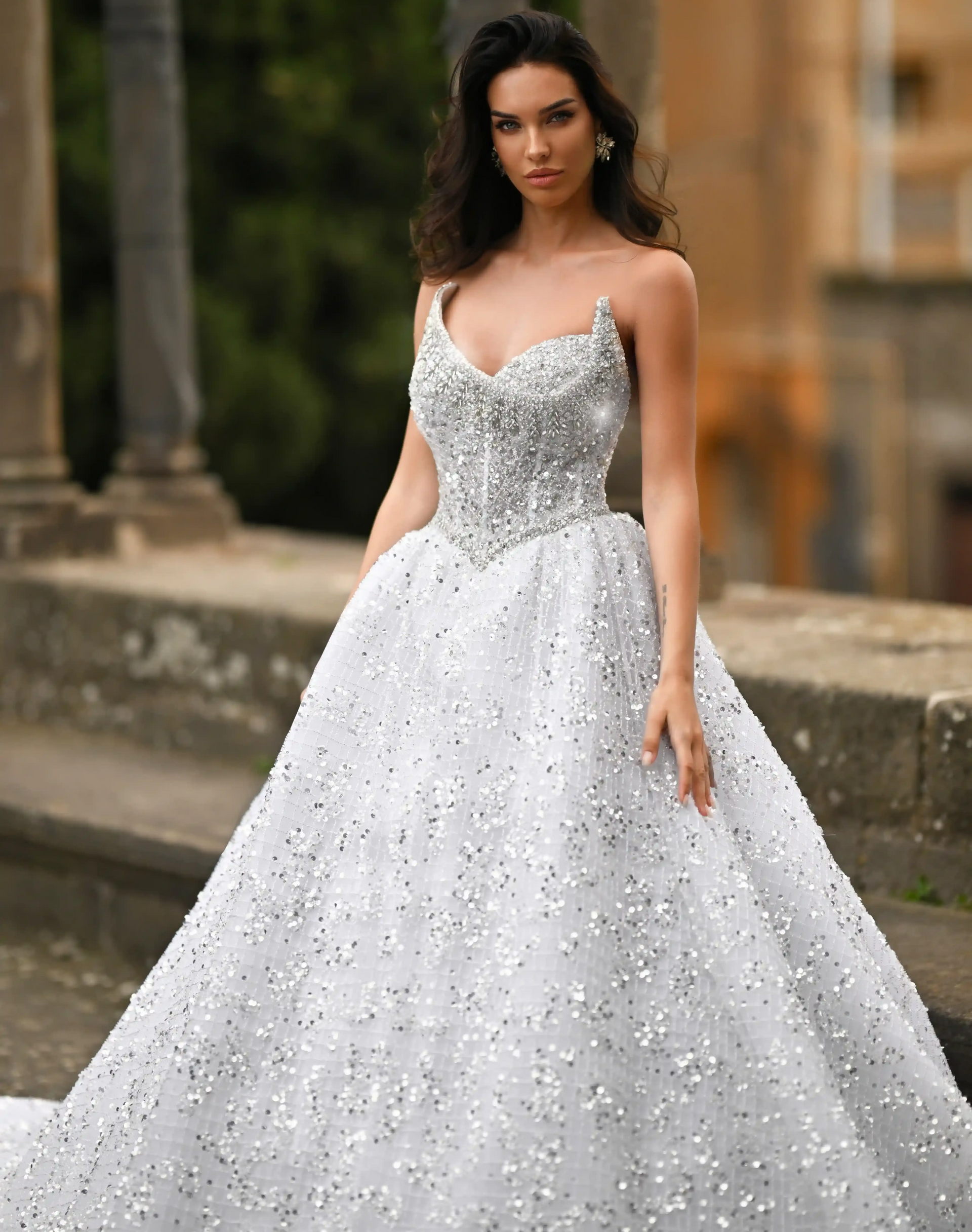 Woman in a white ball gown standing outdoors on a stone walkway