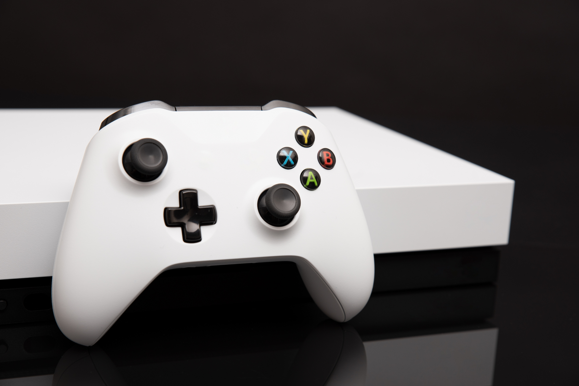 A white video game controller is sitting on top of a white box.