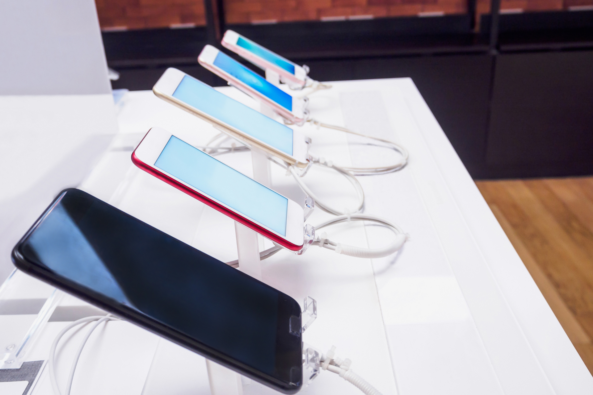 A row of cell phones sitting on top of a table.