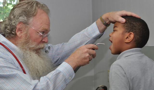 A man with a beard is examining a young boy.