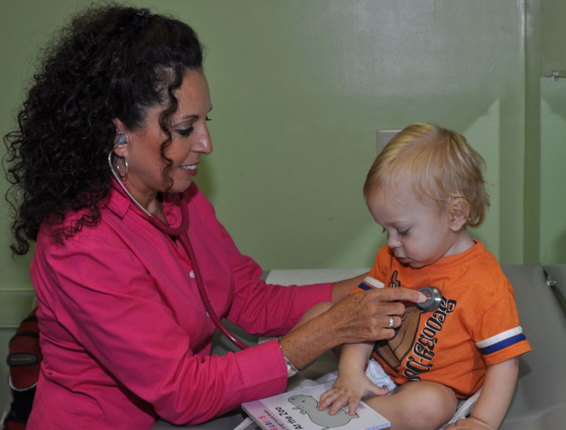A female doctor is examining a baby with a stethoscope.