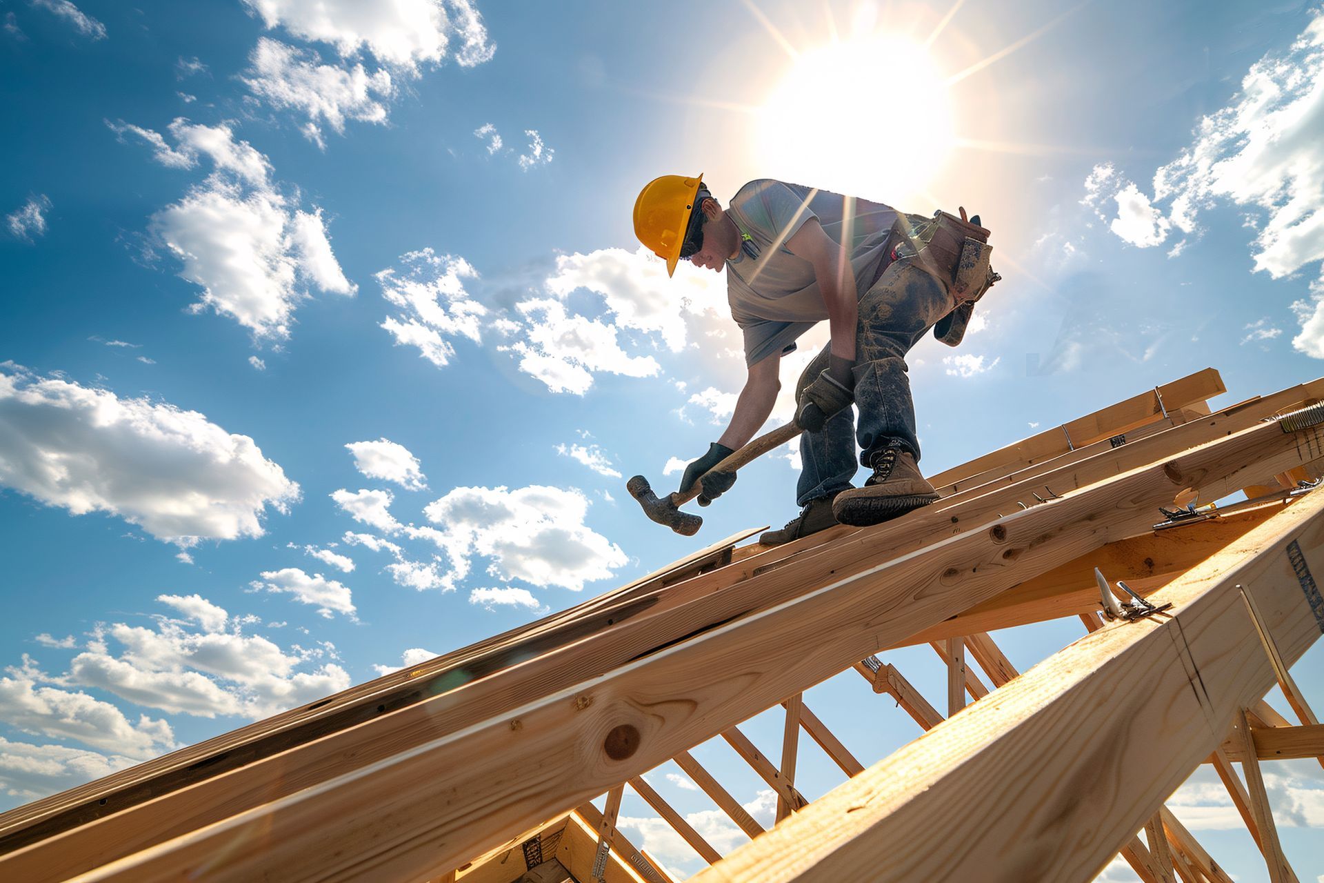 Construction worker hammering wooden roof frame under bright blue sky