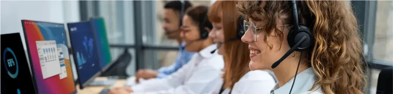 Representantes de atendimento ao cliente usando fones de ouvido, trabalhando em computadores em um ambiente de escritório.