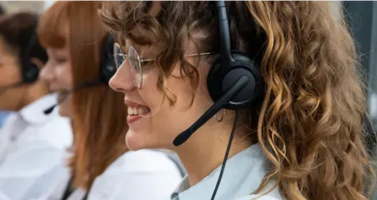 Pessoas usando fones de ouvido, sorrindo enquanto trabalham em um escritório.