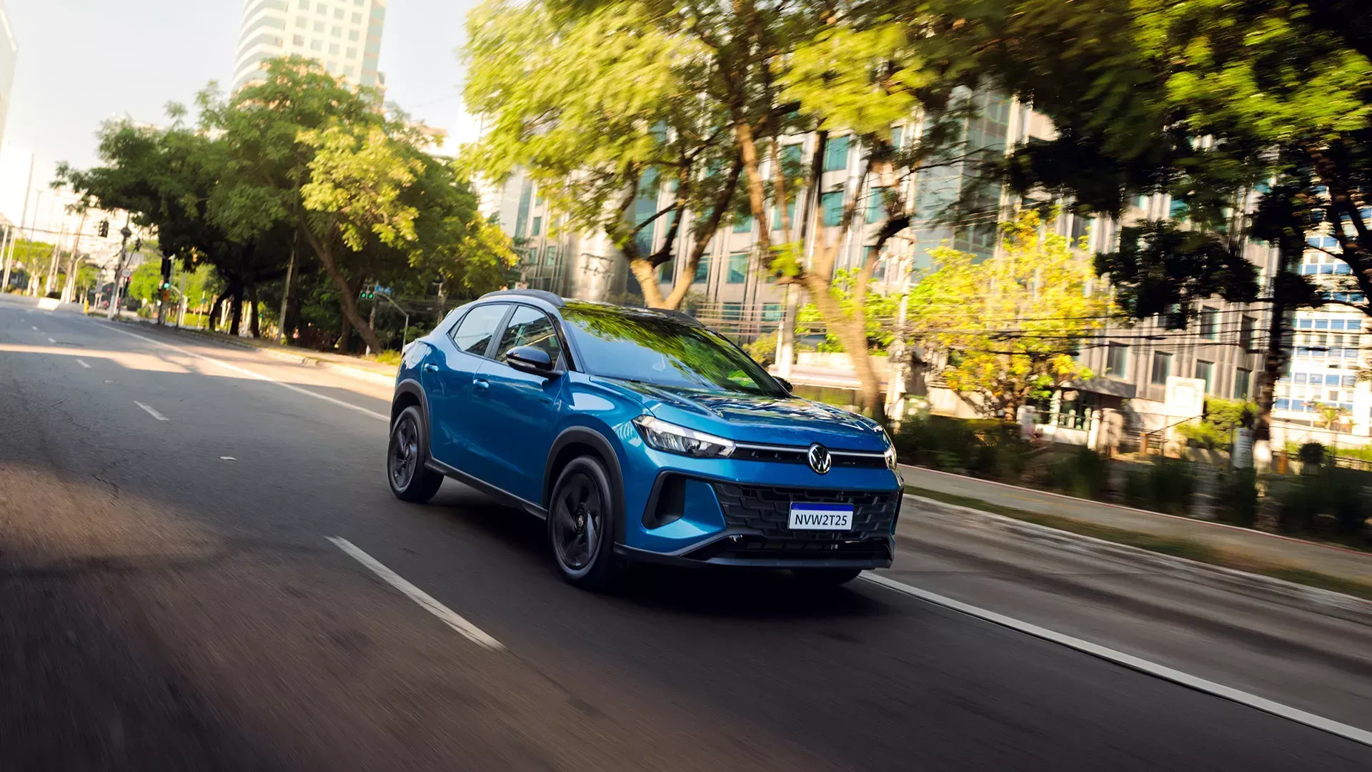SUV azul dirigindo em uma rua da cidade com árvores e prédios ao fundo.