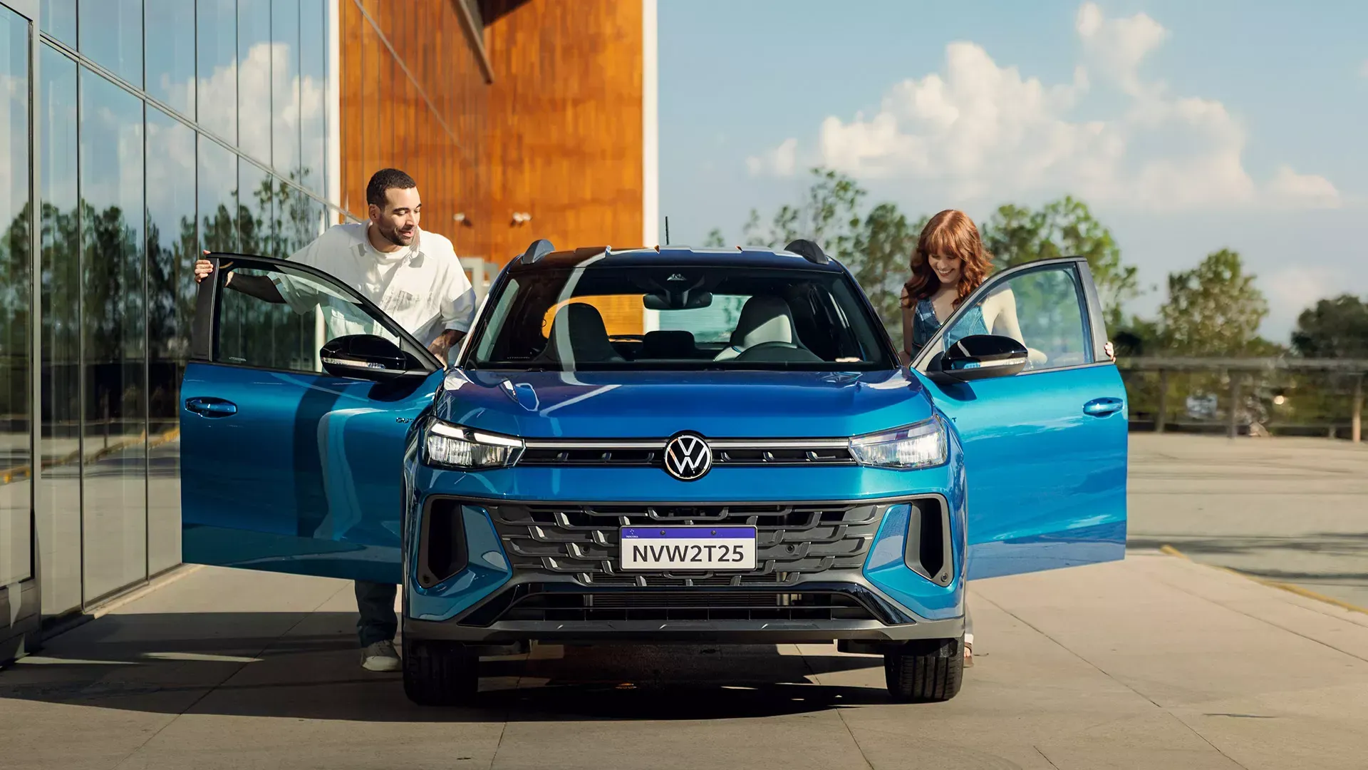SUV Volkswagen azul com portas abertas; casal ao lado. Ao fundo, prédio moderno.