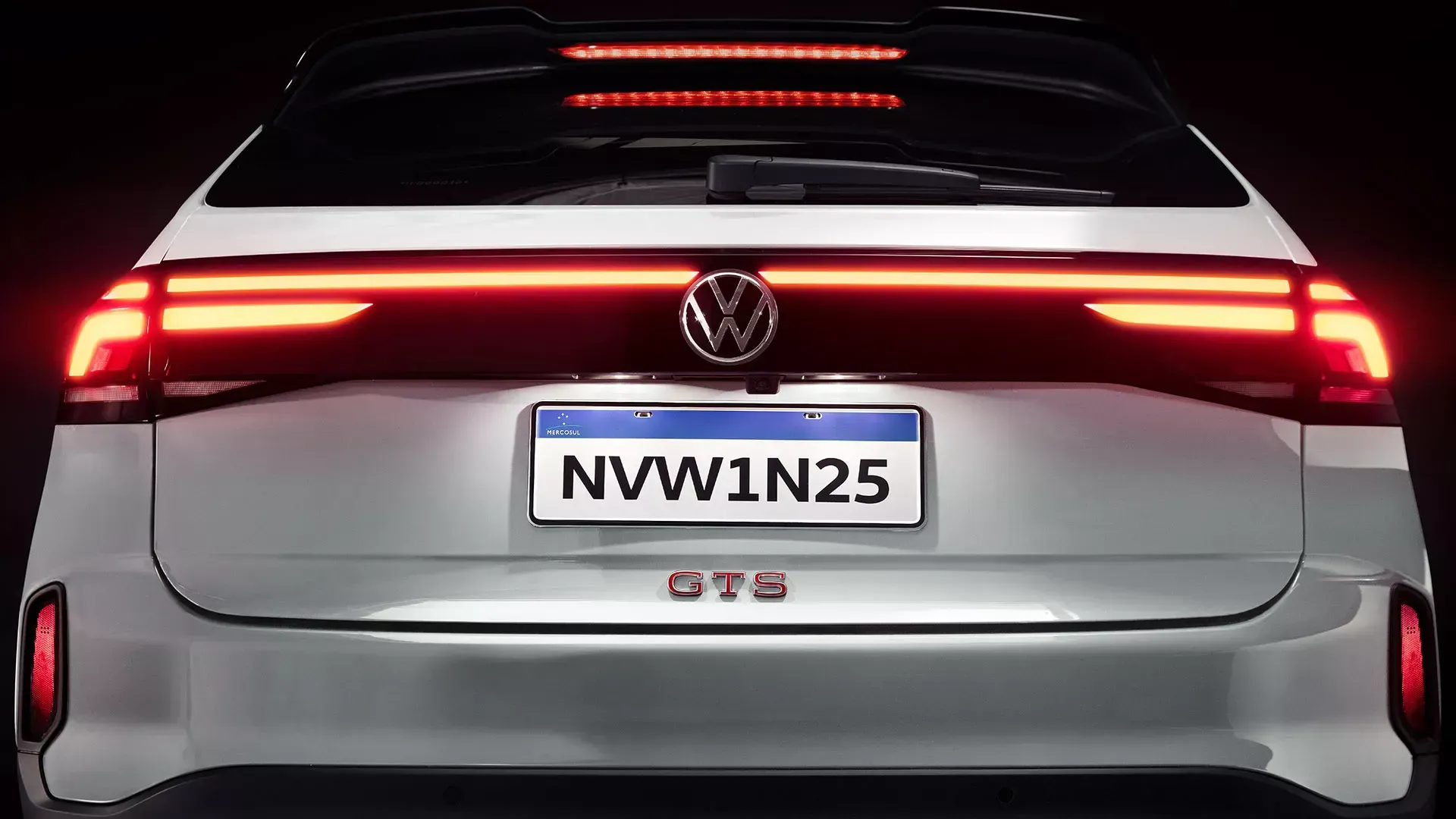 Parte traseira de um carro Volkswagen branco com lanternas traseiras vermelhas iluminadas e emblema 