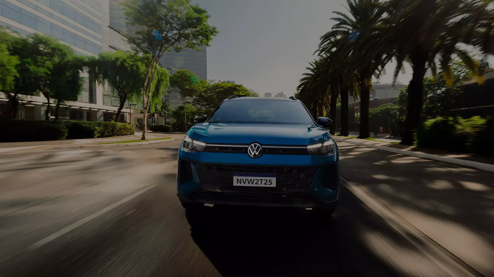 SUV Volkswagen azul dirigindo em uma rua da cidade com palmeiras em um dia ensolarado.