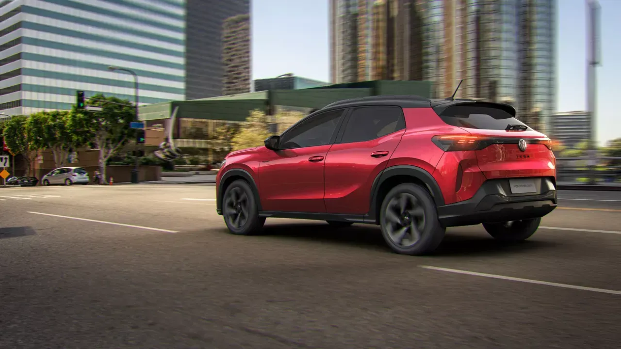 SUV Buick vermelho dirigindo em uma rua da cidade, com prédios altos ao fundo.