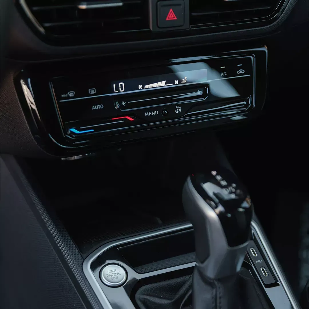 Interior do carro: controles de climatização, câmbio e botão de partida em um veículo moderno.