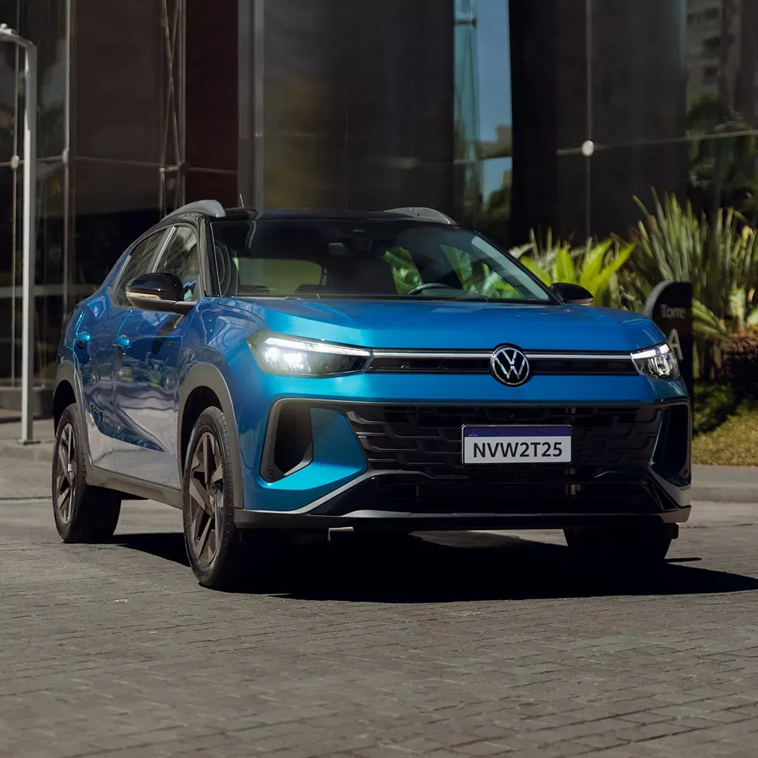 Carro Volkswagen Nivus azul estacionado em frente a um edifício moderno.