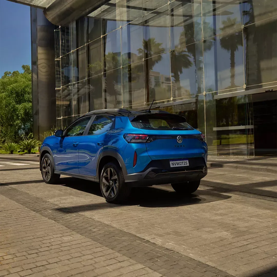 SUV elétrico azul estacionado em frente a um prédio com fachada de vidro.